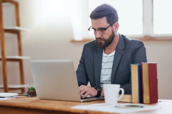 Siempre está trabajando duro. Recortado disparo de un joven hombre de negocios guapo trabajando en su computadora portátil mientras estaba sentado en la oficina en casa. — Foto de Stock