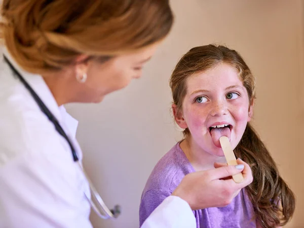 Ora di 'aaah. Girato di un pediatra che esamina una bambina nel suo ufficio. — Foto Stock