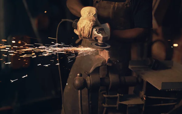 To make art, youve got to make a spark. Shot of a man using an angle grinder while working at a foundry. — Stock Photo, Image