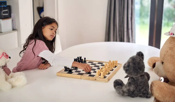 Lærer bort teddyene sine. Sprengt bilde av ei lita jente som spiller sjakk med bamsene hjemme. – stockfoto