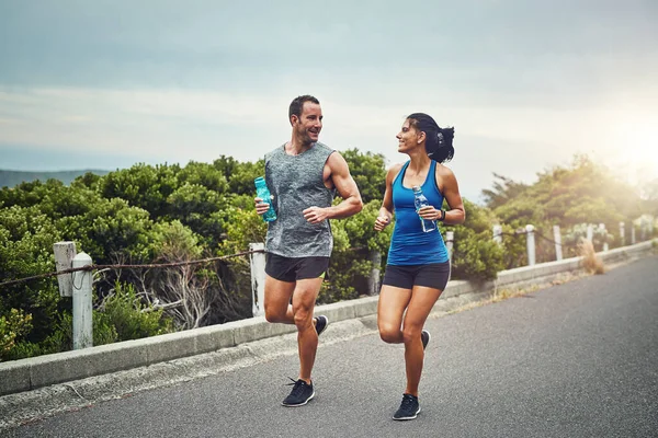 Poznaliśmy się dzięki sprawności fizycznej. Zdjęcia młodej atrakcyjnej pary szkolącej się do maratonu na świeżym powietrzu. — Zdjęcie stockowe