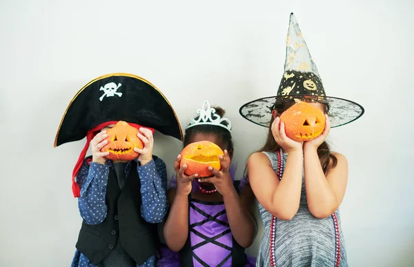 ¿Qué pasa, calabaza? Un disparo de un grupo de niños irreconocibles cubriéndose la cara con calabazas en una fiesta. — Foto de Stock