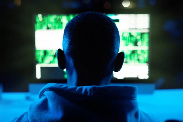 Segera semua informasimu akan menjadi milikku. Rearview shot dari seorang hacker laki-laki retak kode komputer dalam gelap. — Stok Foto