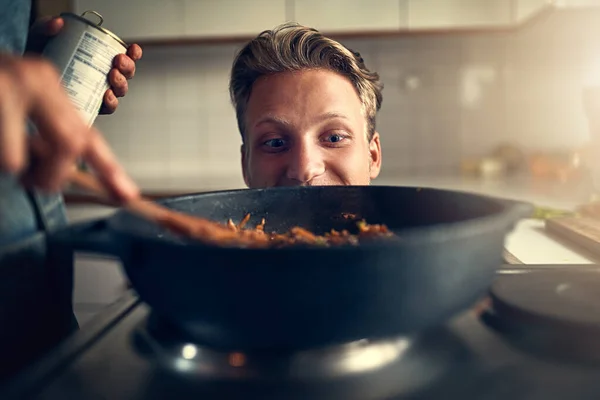 Het ruikt lekker. Schot van jonge man kijken naar zijn moeder koken op het fornuis in hun keuken thuis. — Stockfoto