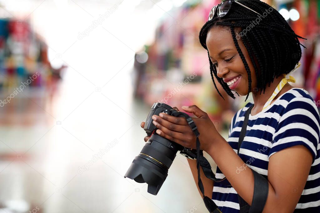 Ive got some great pics so far. A young female tourist looking through her photographs while standing in a grocery store.