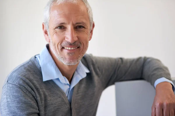 Entspannt und selbstbewusst. Porträt eines gestandenen Geschäftsmannes, der sich im Büro an seinen Computer lehnt. — Stockfoto