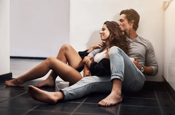 L'amour se transforme d'un endroit à une personne. Tourné d'un jeune couple affectueux assis sur le sol de la cuisine. — Photo