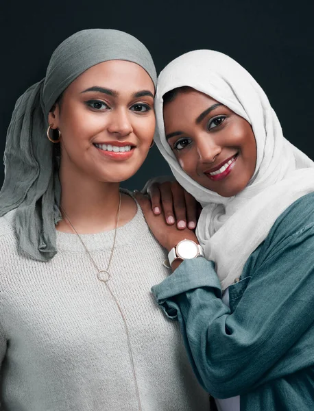Vrienden tot het einde. Gehakt schot van twee aantrekkelijke jonge vrouwen dragen hijabs en staan dicht bij elkaar tegen een zwarte achtergrond in de studio. — Stockfoto
