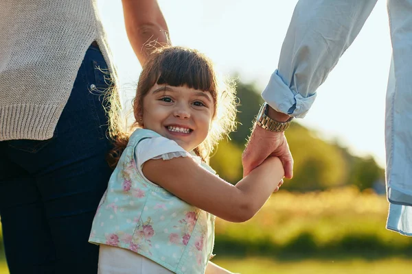 En dan gaan we naar het park. Portret van een schattig en gelukkig klein meisje met haar moeder en vaders handen in het park. — Stockfoto