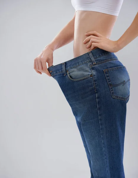 Você pode conseguir isso também. Tiro cortado de uma mulher mostrando seu perda de peso com um grande par de calças. — Fotografia de Stock