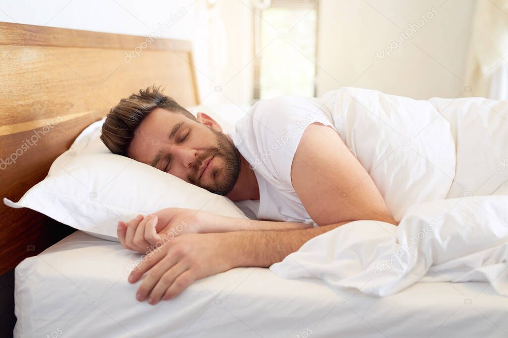 Time to enjoy a weekend lie-in. Cropped shot of a young man sleeping peacefully in bed at home.