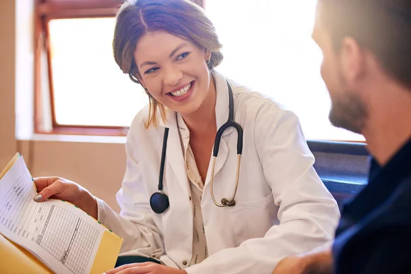 Sus resultados están en, y se ven muy bien. Inyección de un joven médico consultando con un paciente en su consultorio. — Foto de Stock