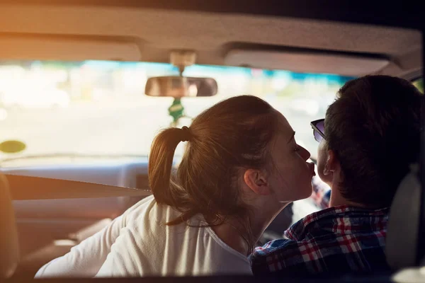 Alguns beijos não podem esperar. Retrovisor tiro de uma jovem mulher beijando seu namorado enquanto ele dirige um carro. — Fotografia de Stock