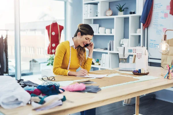 Ik neem altijd graag een andere klant aan. Gesneden foto van een aantrekkelijke jonge modeontwerpster in haar atelier. — Stockfoto