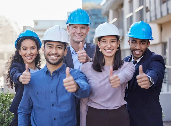 Laat het gebouw aan ons over. Opname van een diverse groep zakenmensen die samen staan en een duim omhoog laten zien terwijl ze een helm op hebben. — Stockfoto