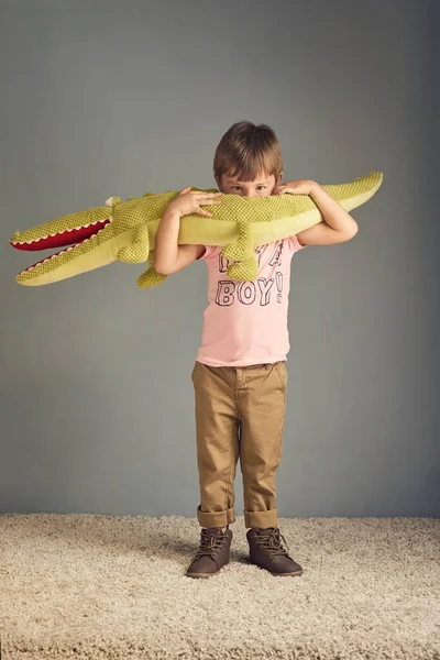 Mi sono appena beccato un grande vecchio alligatore. Studio ritratto di un adorabile bambino che gioca con un giocattolo di coccodrillo su uno sfondo grigio. — Foto Stock