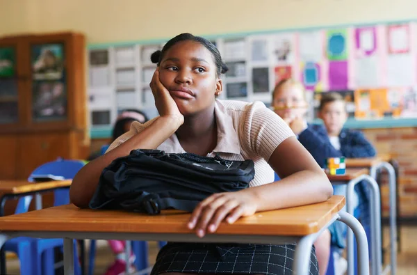 Argh, its going to be a long day. Shot of a young girl sitting in her classroom at school and feeling bored. — Stock Photo, Image