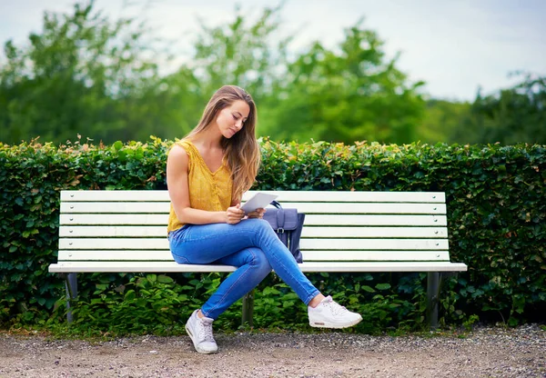 Wifi en el parkconvenience se encuentra con la conectividad. Fotografía de una joven usando una tableta digital en un banco del parque. — Foto de Stock