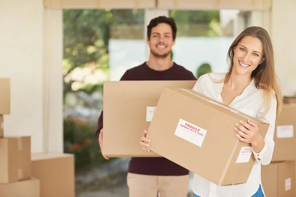 Estas son las últimas cajas. Retrato de una joven pareja sonriente llevando cajas mientras se mudan a su nuevo hogar. — Foto de Stock
