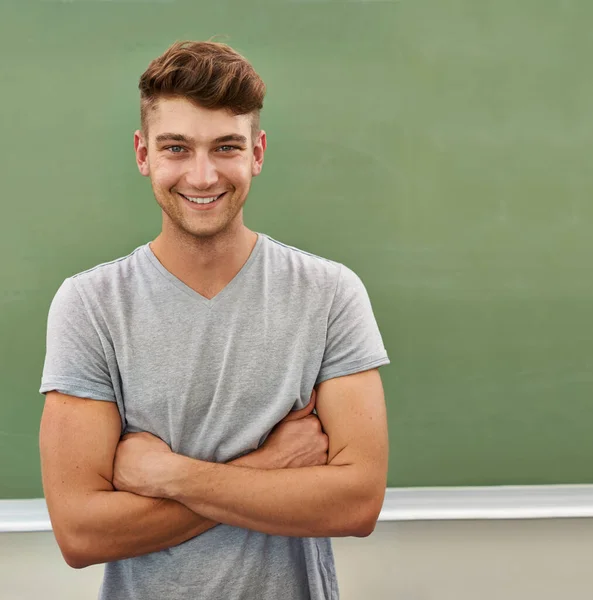 Wie wäre es mit einer Lehrerkarriere? Ein junger Mann lächelt in die Kamera, während er vor einer Tafel steht. — Stockfoto