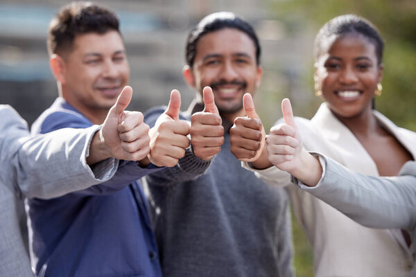 Its a yes from us. Portrait of a group of businesspeople showing a thumbs up outside.