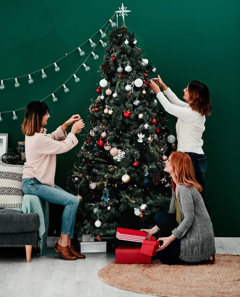 Hepimiz üzerimize düşeni yapıyoruz. Evde Noel ağacını süsleyen üç çekici orta yaşlı kadının fotoğrafı.. — Stok fotoğraf