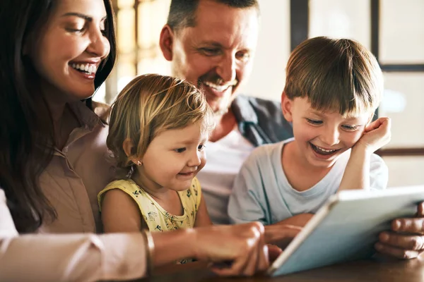 Dodaję czas ekranu do czasu rodzinnego. Zdjęcie czteroosobowej młodej rodziny z tabletem cyfrowym w domu.. — Zdjęcie stockowe