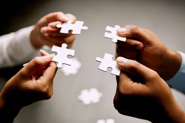 Which one is the best fit. Closeup shot of a group of unrecognizable businesspeople holding puzzle pieces together.
