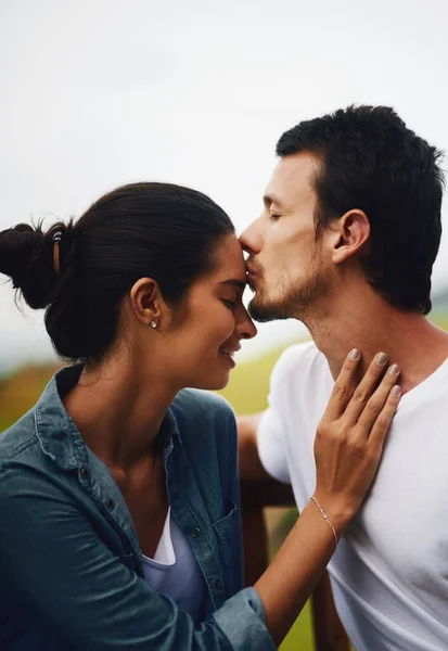 Voorhoofd kussen, het mooiste gevoel in de wereld. Opname van een liefdevol jong koppel dat een romantische dag doorbrengt in het park. — Stockfoto