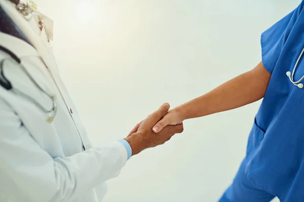 La colaboración va muy lejos en medicina. Foto de ángulo alto de dos profesionales de la salud no identificables estrechando la mano en el vestíbulo del hospital. —  Fotos de Stock