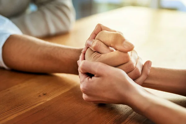 Podemos hacer esto juntos. Recorte de dos personas irreconocibles cogidas de la mano mientras se sientan en una mesa dentro durante el día. —  Fotos de Stock