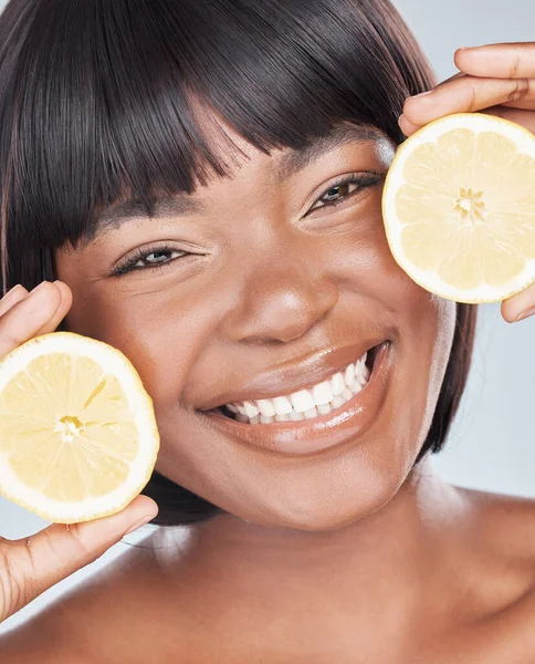 Niets voegt meer waarde toe aan mijn huid dan vitamine C. Studio shot van een aantrekkelijke jonge vrouw met een citroen in haar gezicht tegen een grijze achtergrond. — Stockfoto