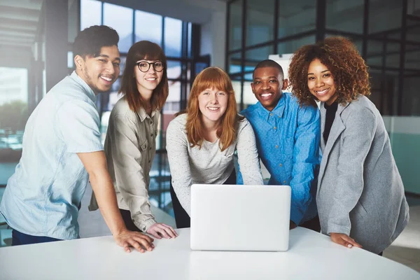 Moderne technologie geeft het voordeel op. Gesneden portret van een groep jonge zakenmensen die in hun kantoor rond een laptop huppelden. — Stockfoto