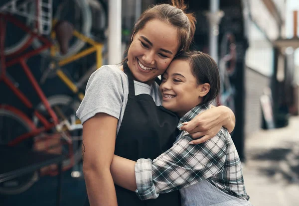 En realidad somos familia. Fotografía de dos jóvenes colegas compartiendo un abrazo fuera de un taller de reparación de bicicletas. —  Fotos de Stock