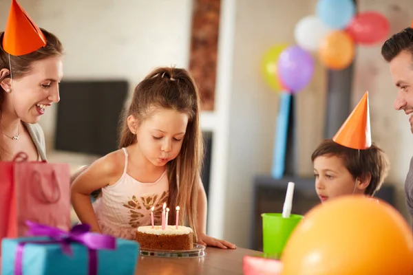 De kaarsen blazen terwijl je een wens doet. Gekropte foto van een familie die thuis een verjaardag viert. — Stockfoto