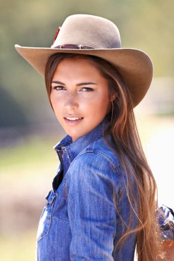 Are yaall ready for me. Portrait of an attractive young cowgirl standing in the sun. clipart