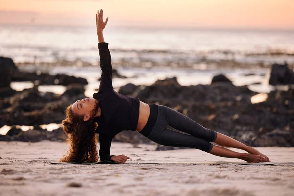 Adem door elke houding. Shot van een aantrekkelijke jonge vrouw doen yoga alleen op het strand bij zonsondergang. — Stockfoto