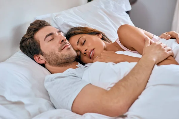 Att somna i kärlek omfamnar. Skjuten av ett kärleksfullt ungt par som ligger med varandra hemma. — Stockfoto