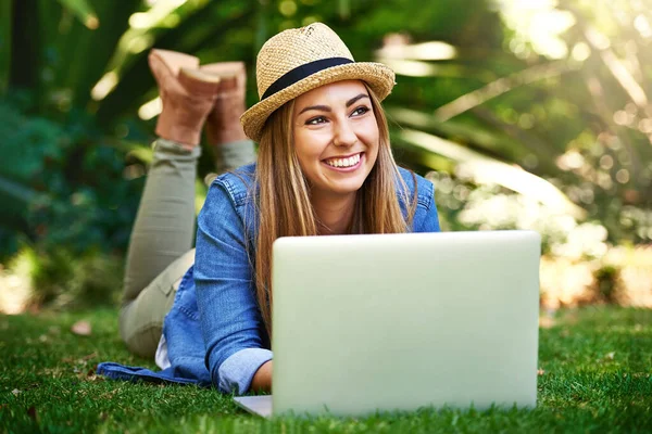 Ik denk aan haar volgende artikel. Shot van een aantrekkelijke jonge vrouw met behulp van haar laptop terwijl buiten op het gras. — Stockfoto