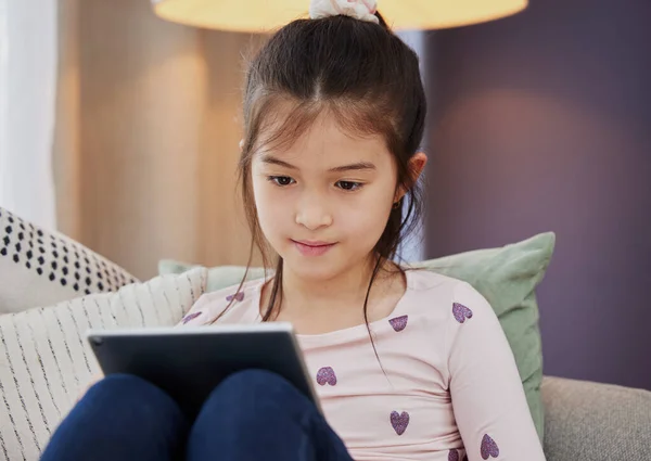 La biblioteca podría estar cerrada, pero Internet no lo está. Fotografía de una adorable niña usando una tableta digital mientras está sentada en casa. — Foto de Stock