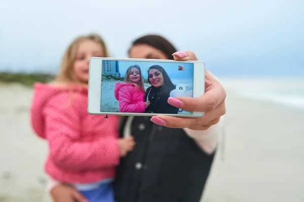 让珍贵的记忆。一个母亲和她年幼的女儿在海滩上自拍的剪影. — 图库照片