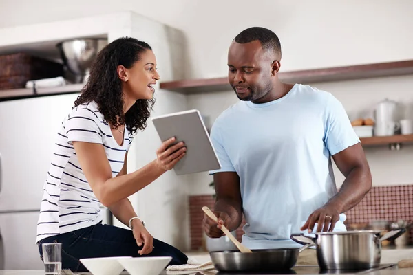 Vamos ver o que diz o aplicativo de culinária. Tiro cortado de um jovem casal usando um tablet enquanto cozinham juntos na cozinha em casa. — Fotografia de Stock