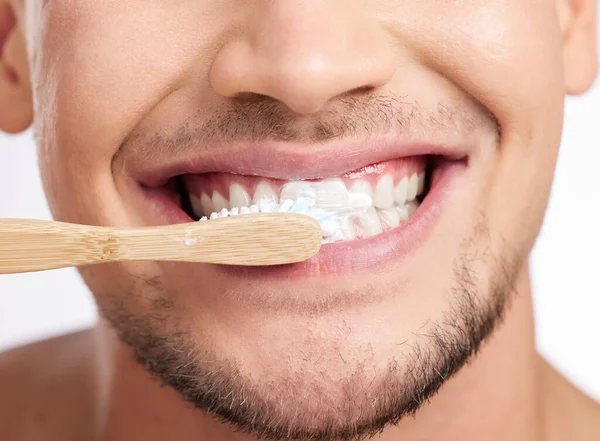 Haciendo mantenimiento bucal. Estudio de un hombre irreconocible cepillándose los dientes contra un fondo gris. — Foto de Stock