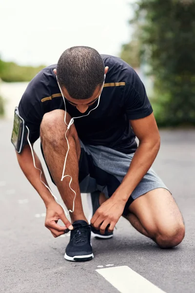 Si prepara a intensificare il suo gioco di fitness. Girato di un giovane sportivo legare i lacci mentre fuori per una corsa. — Foto Stock
