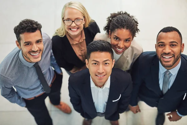 Als je een leider bent, zorg er dan voor dat je team tegen je opkijkt. Hoog hoekportret van een groep vrolijke jonge zakenmensen die overdag samen op kantoor staan. — Stockfoto