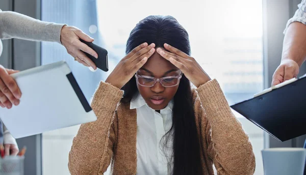 Varför lämnar de mig inte ifred? Skjuten av en ung affärskvinna som sitter på kontoret och känner sig stressad medan kollegor överväldigar henne med uppgifter. — Stockfoto