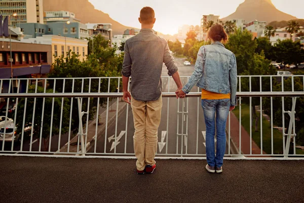 Amor urbano. Rearview tiro de um casal de pé juntos em uma ponte da cidade e olhando para a vista. — Fotografia de Stock