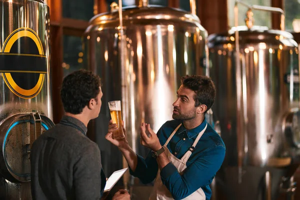 Es dreht sich alles um den Geschmack. Aufnahme von zwei jungen Arbeitern bei der Inspektion ihrer Bierherstellungsmaschinen in einer Bierbrauerei während des Tages. — Stockfoto