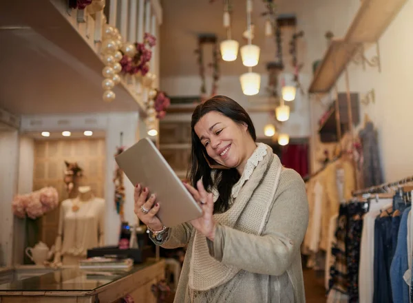 Lieferungen nachverfolgen. Schnappschuss einer attraktiven, reifen Unternehmerin, die in ihrer eigenen Boutique an einem Tablet arbeitet. — Stockfoto