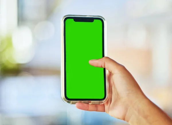 Sempre ligado. Uma jovem segurando um smartphone com uma tela verde contra um fundo desfocado.. — Fotografia de Stock